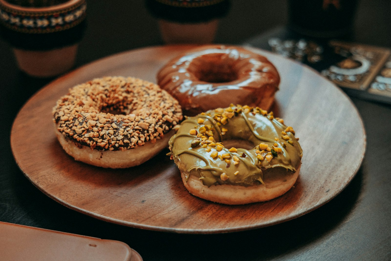 Three decorated donuts on a wood plate beside coffee. Representative stock photo.